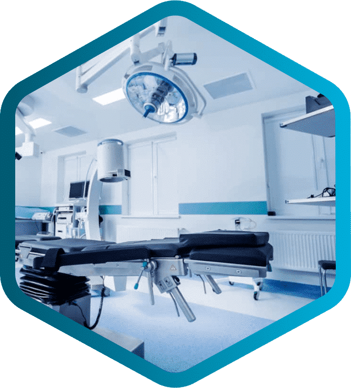 A modern, empty operating room with surgical lights, equipment, and an adjustable operating table—expertly maintained by Biomedical and Clinical Engineers—shown within a blue hexagonal border.