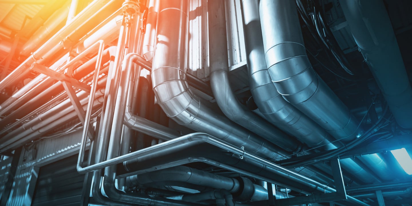 Industrial pipes and ductwork with metallic surfaces intersect and curve within a brightly lit interior space, seamlessly integrating fluid equipment handling systems.