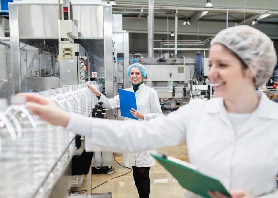 Woman checking bottle on assembly line