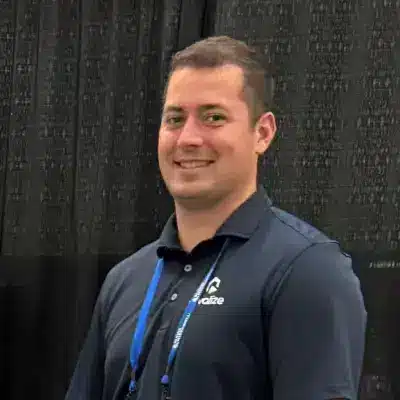 A person in a navy ProFood Welt polo shirt with a logo stands in front of a black curtain, smiling at the camera.